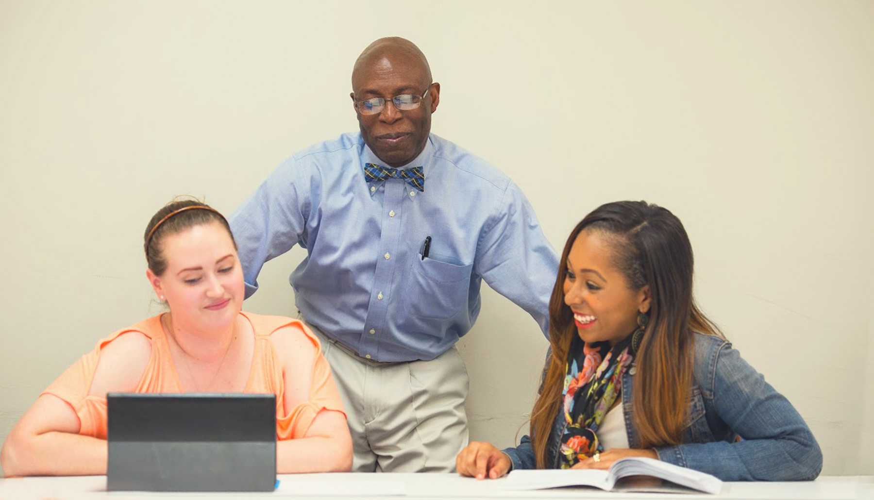 a male professor in a bowtie working with two students