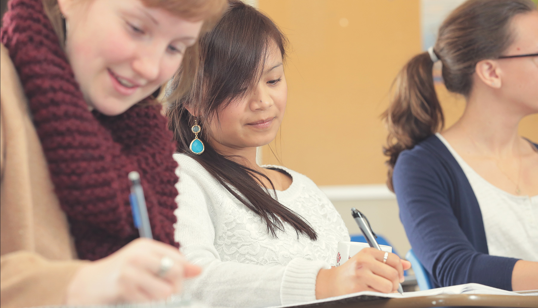 three students taking notes