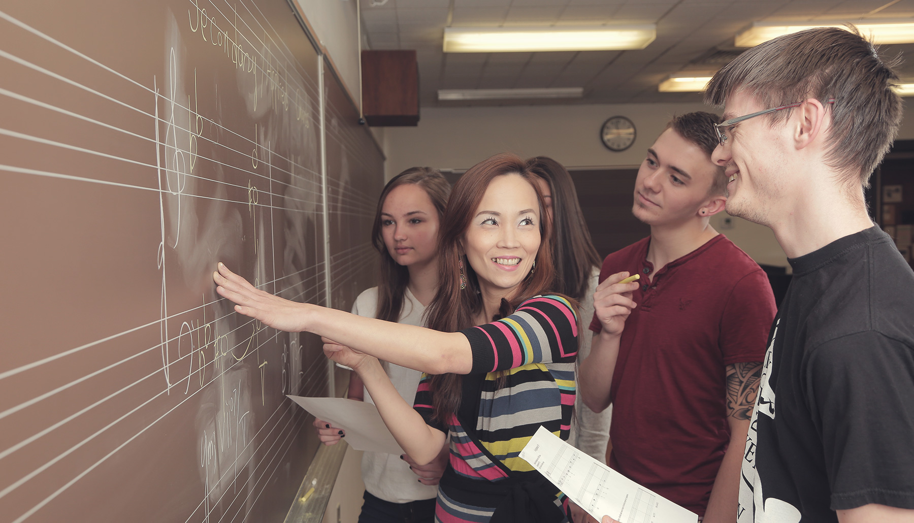a female professor works with students at a chalkboard