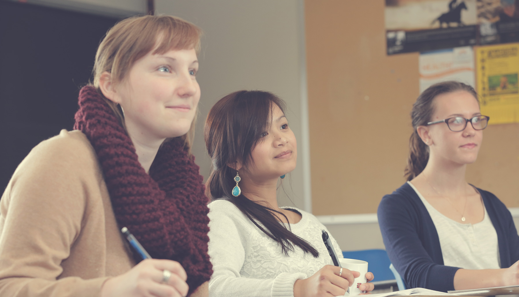 three young women engaged in coursework