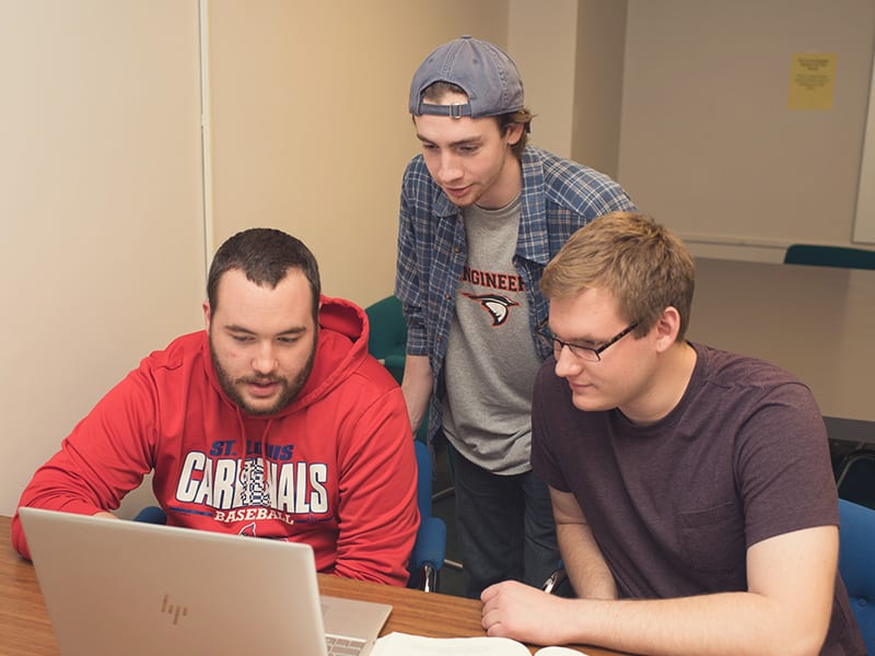Students crowding around one computer to work.